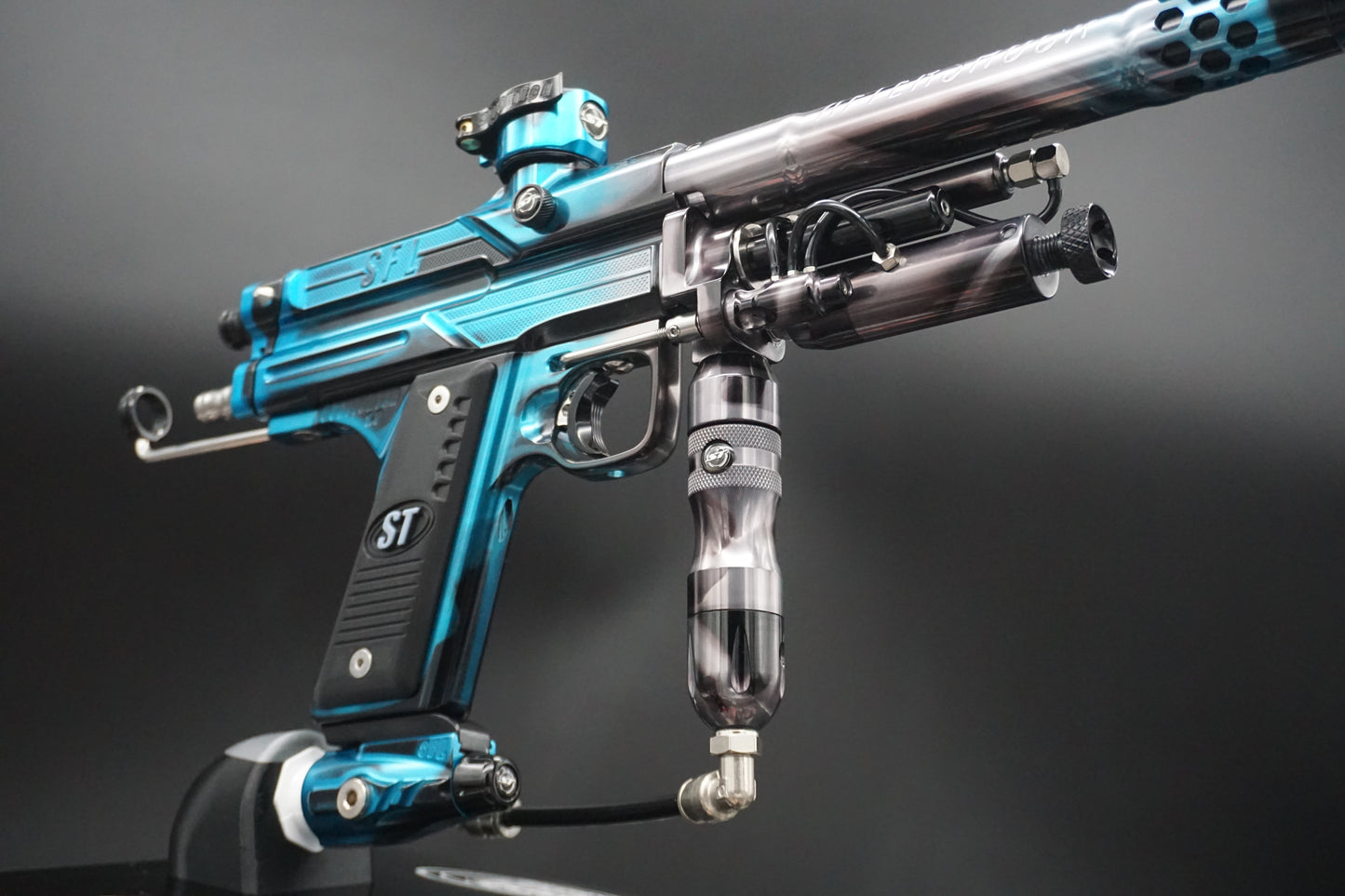 Close-up of a blue and black paintball gun on a gray background