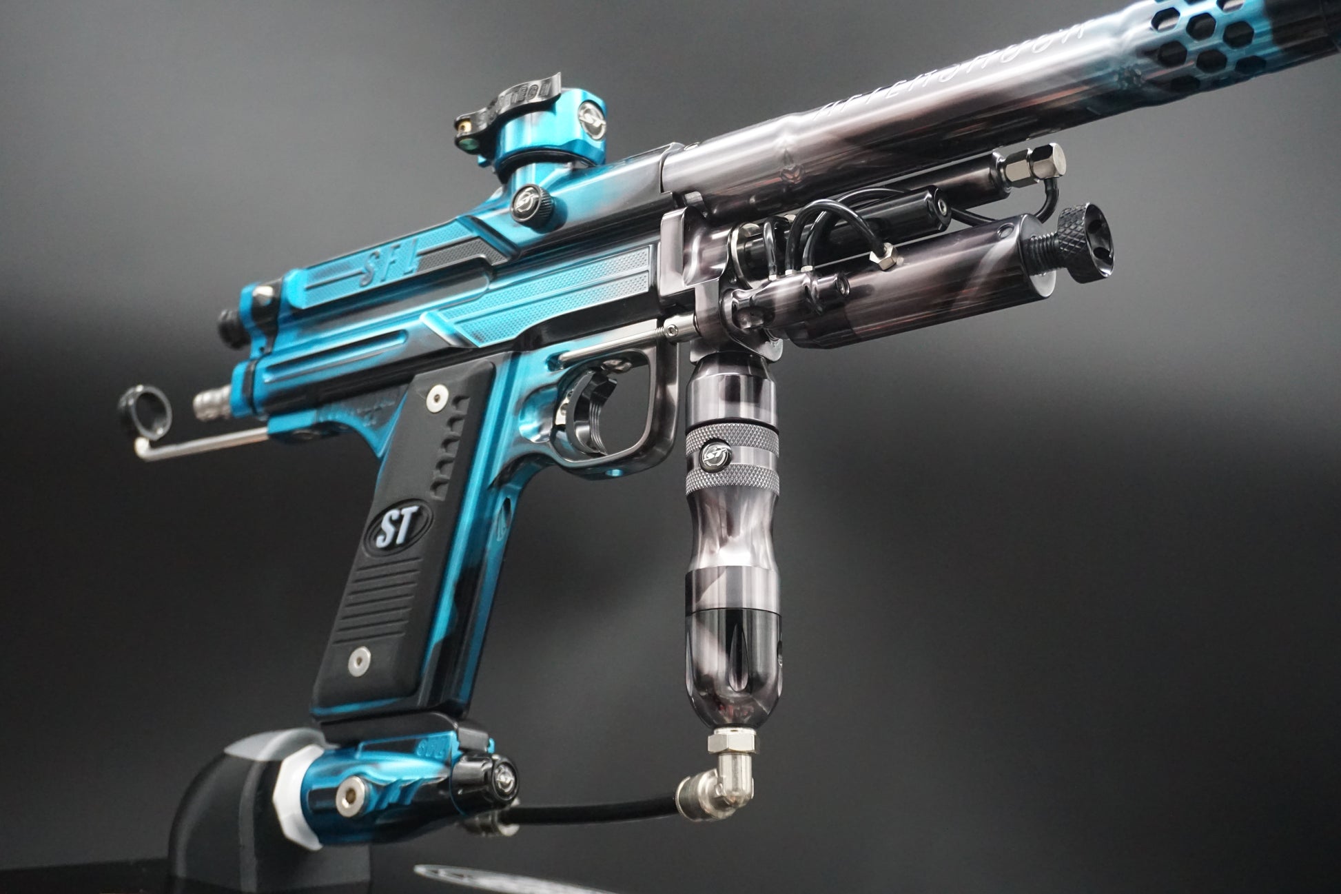 Close-up of a blue and black paintball gun on a gray background